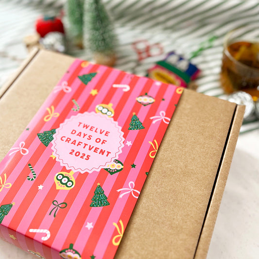 Gift box with a pink and brown design featuring 'Twelve Days of Craftvent 2023' on a white surface.