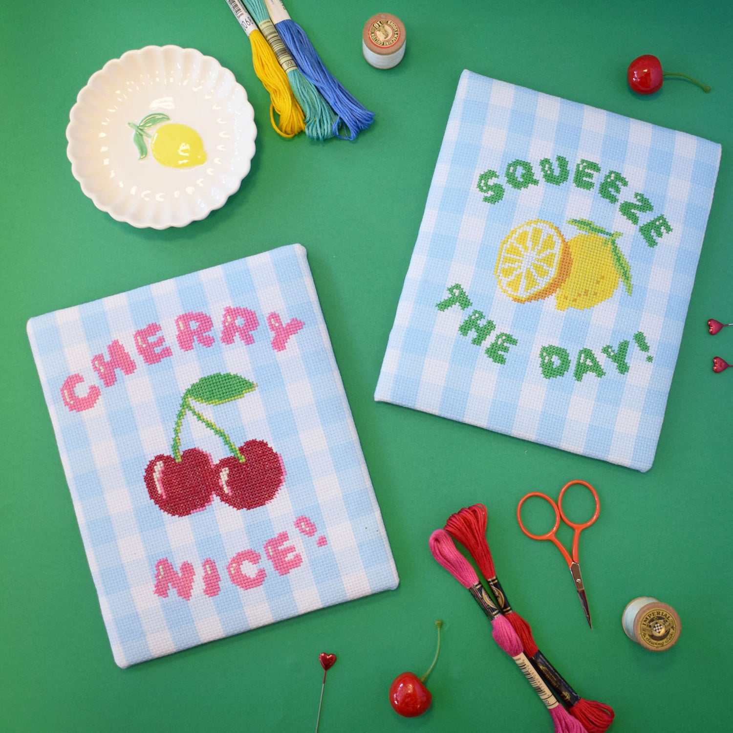 a set of cross stitch designs - one with 'cherry nice' and one with 'squeeze the day' with a cherry and lemon design.
