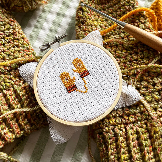 Embroidery hoop with cross-stitched design on a textured crochet background