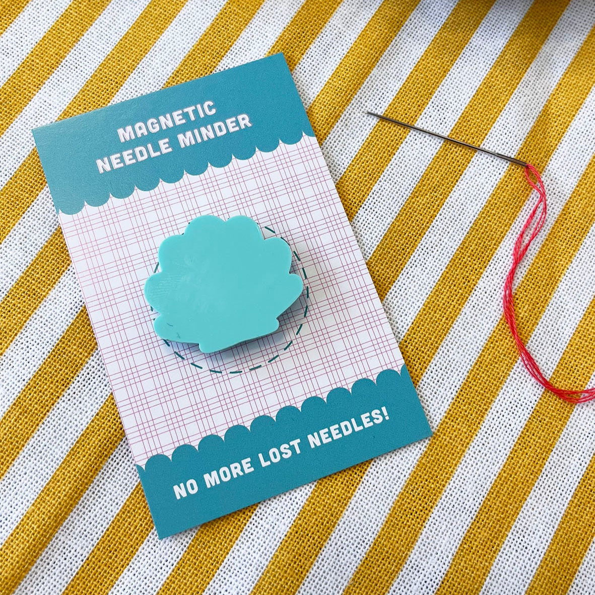 mint green coloured shell shaped acrylic needle minder on a stripe yellow background.
