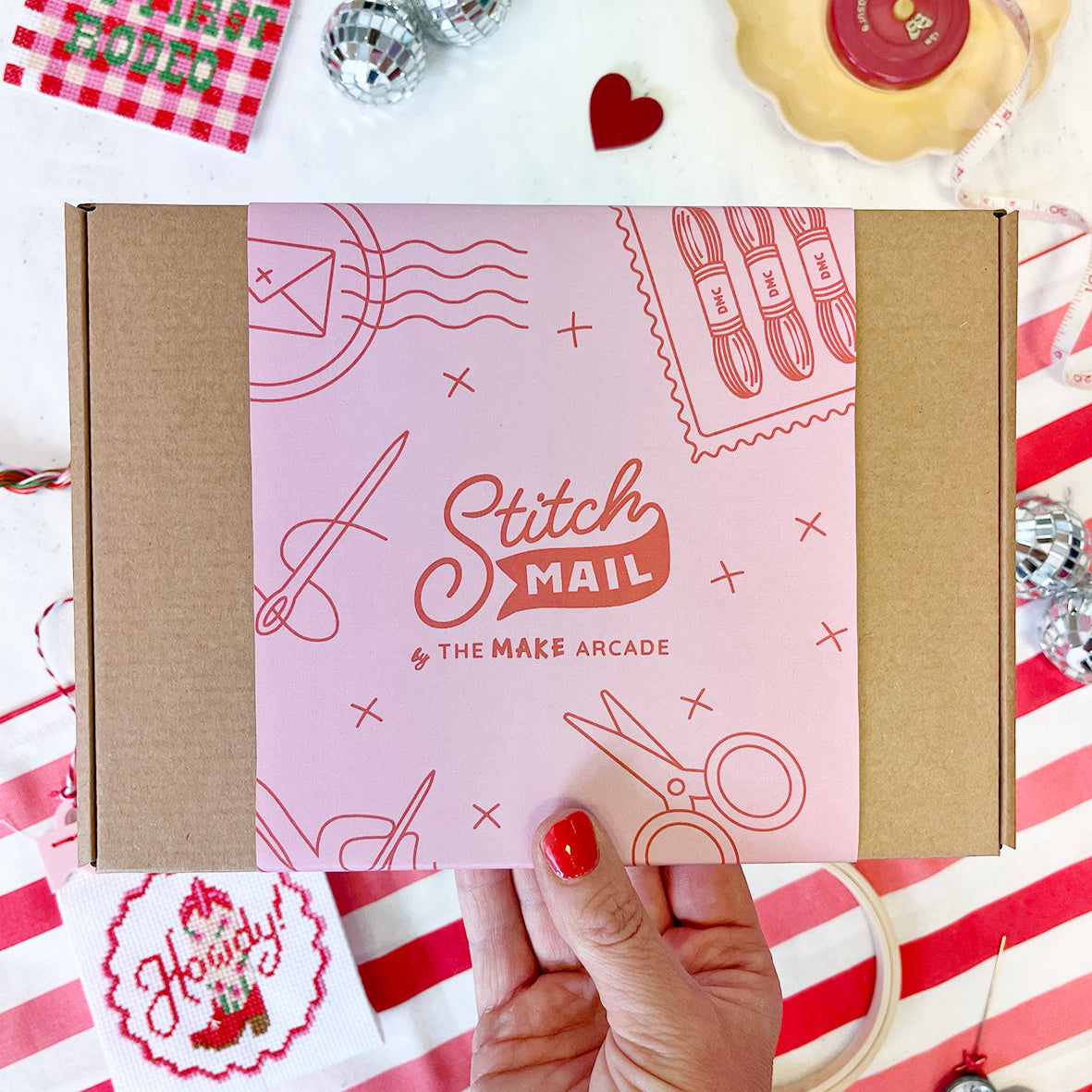 Stitch Mail box held by a hand on a red and white striped background with decorative items.