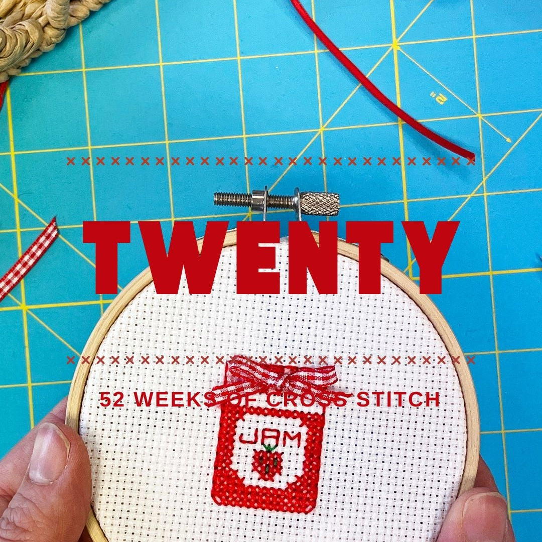 Cross-stitched strawberry jam design on a blue cutting mat