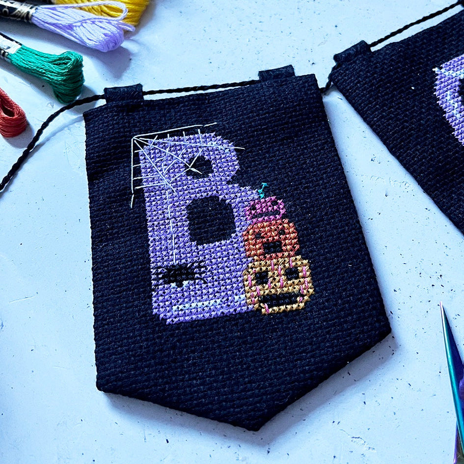 halloween cross stitch garland with the word 'BOO' spelt across it.