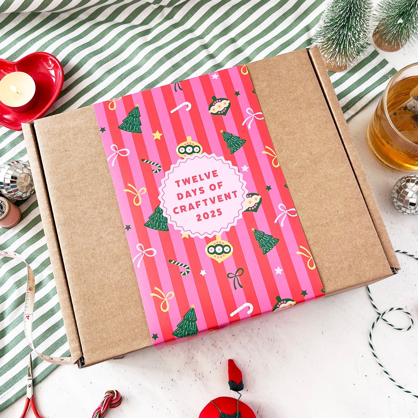 Box with a pink 'Twelve Days of Craftvent' cover on a striped fabric background