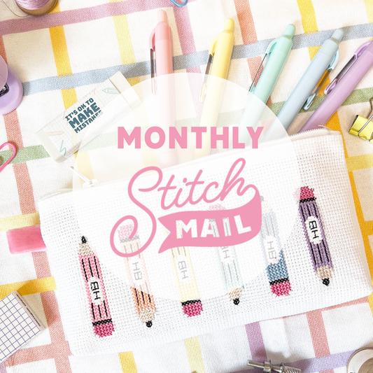 Cross-stitch kit with 'Monthly Stitch Mail' branding on a colorful fabric background.