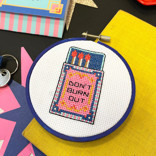 Cross-stitched hoop with 'Don't Burn Out' design on a colorful background