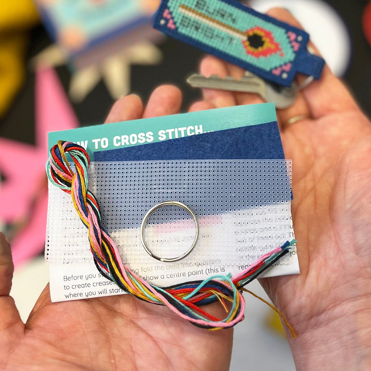 Cross stitch kit with colorful threads and a card on a blurred background