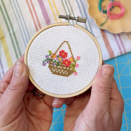 floral cross stitch hanging basket design being held with hands