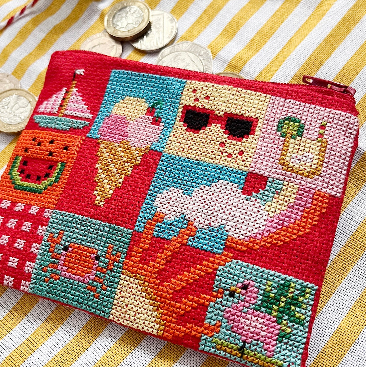 Colourful beaded cross stitch purse with summer-themed design on a striped fabric background
