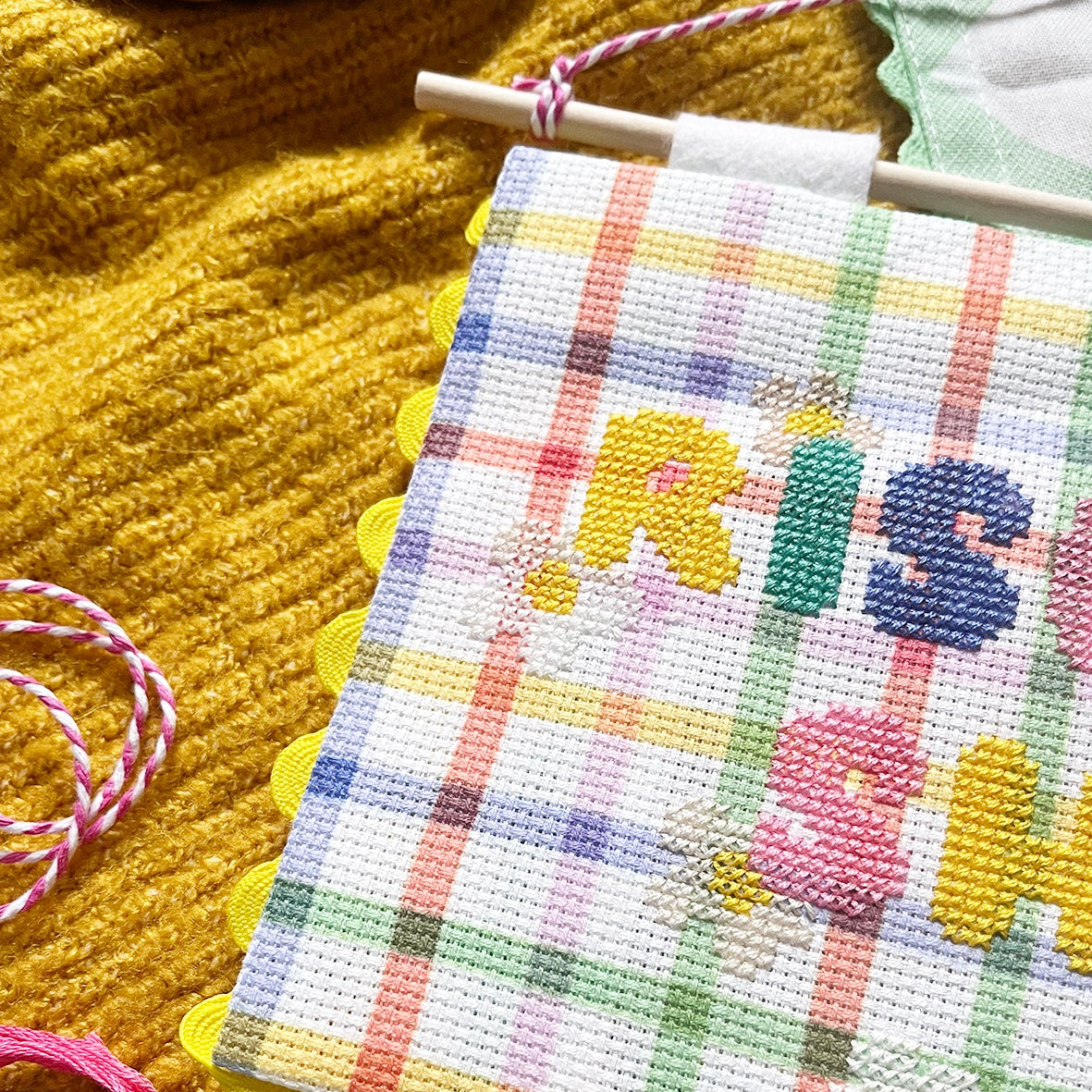 checked aida with cross stitched 'rise and shine' motto on a textured yellow background