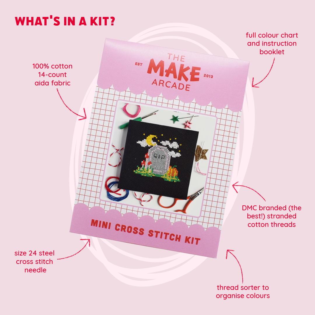 A pink promotional graphic for The Make Arcade Mini Cross Stitch Kit, showing the kit packaging with callout arrows and text describing included items such as cotton aida fabric, a steel cross stitch needle, DMC branded cotton threads, a thread sorter, and a full instruction booklet.
